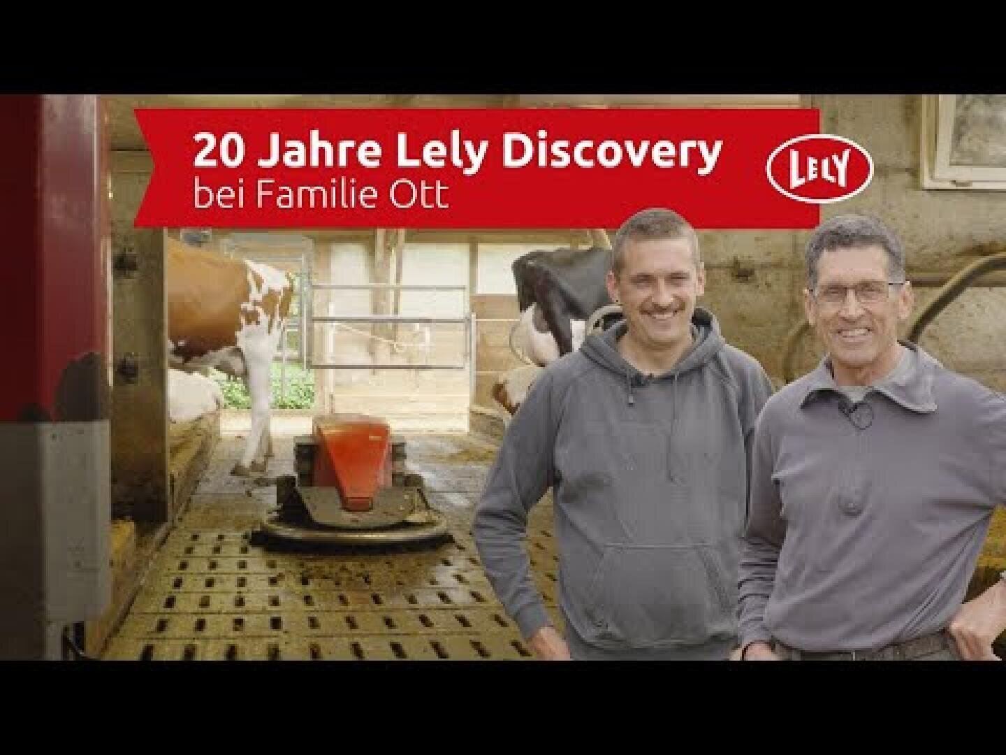 Zwei lächelnde Männer stehen in einer Scheune neben Kühen und landwirtschaftlichen Geräten. Der Text auf dem Bild lautet 20 Jahre Lely Discovery bei Familie Ott mit dem Lely-Logo in der oberen rechten Ecke.