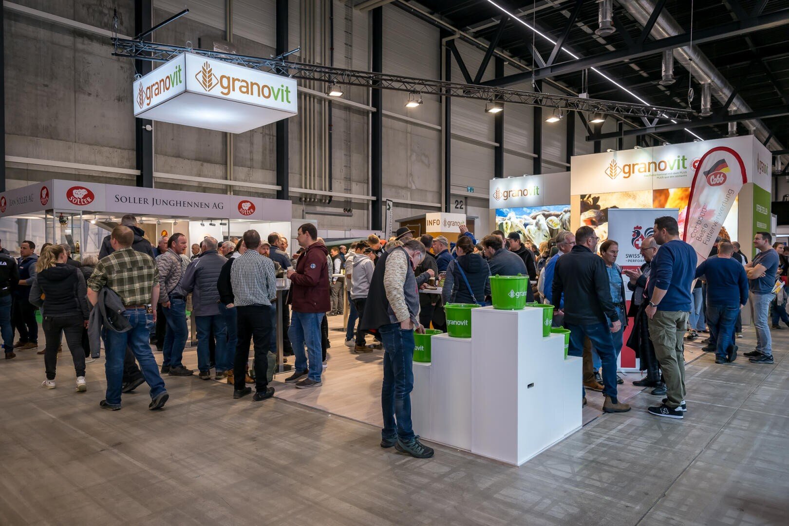 Eine belebte Messehalle mit vielen Menschen, die sich um die Stände scharen, darunter auch prominente Stände von Granovit. Die Teilnehmer unterhalten sich und erkunden die Produkte bei heller Beleuchtung in einem geräumigen, modernen Veranstaltungsort.