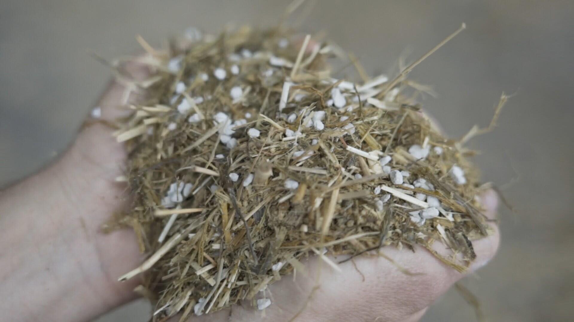 Eine Nahaufnahme von zwei Händen, die eine Mischung aus Stroh, trockenem organischem Material und OmyaFeed®  MgO, vor einem unscharfen Hintergrund halten.