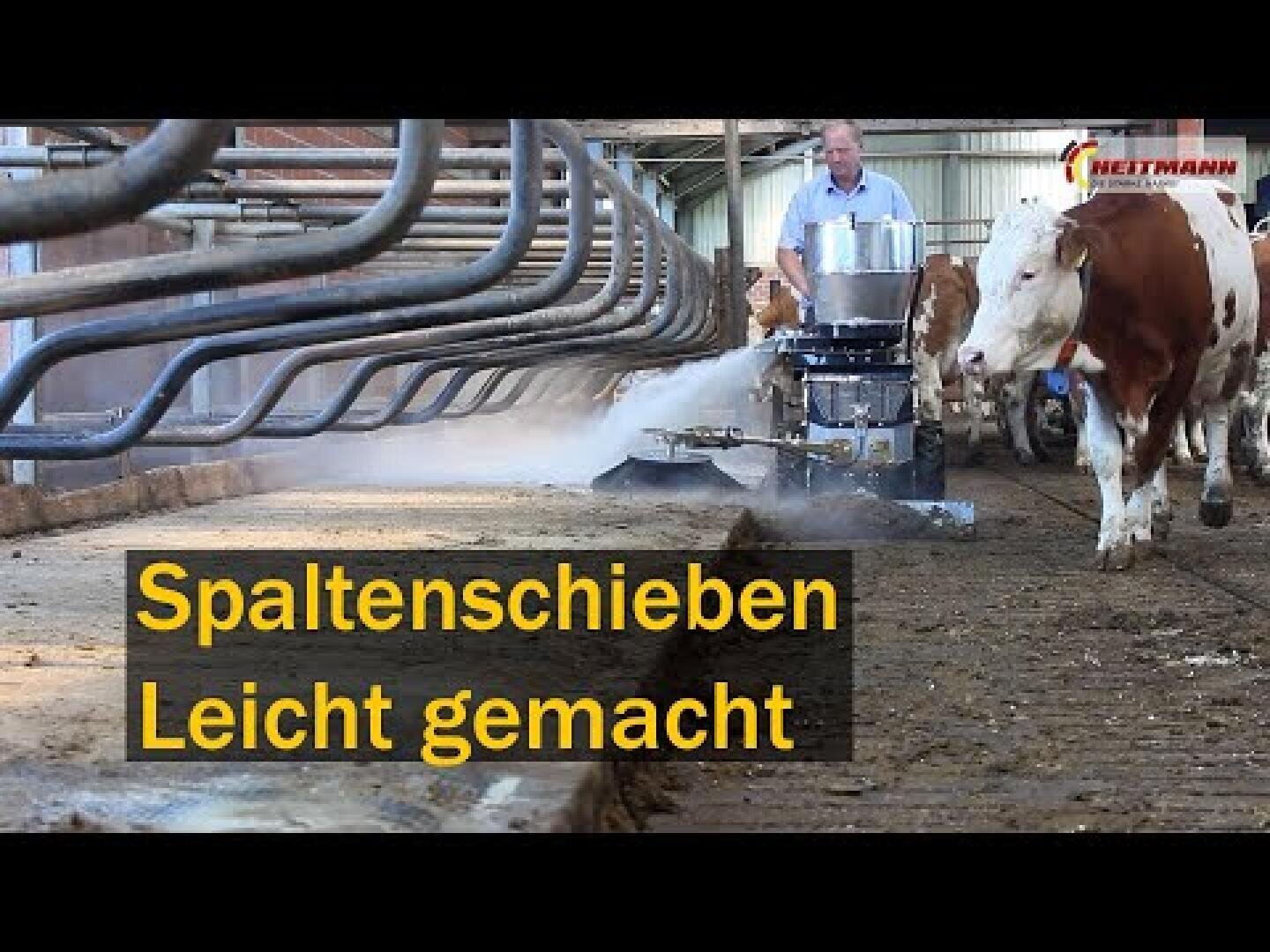 Ein Mann bedient eine Bodenreinigungsmaschine in einem Stall mit Kühen in der Nähe. Der Text Spaltenschieben Leicht gemacht ist gelb überlagert, was auf Deutsch Spaltenreinigung leicht gemacht bedeutet.