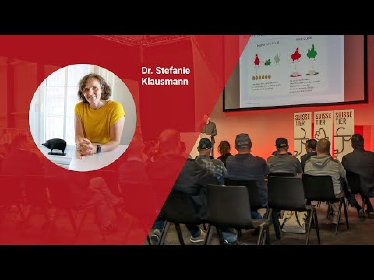 Eine Präsentation zeigt das Foto und den Namen von Dr. Stefanie Klausmann auf rotem Hintergrund, während das Publikum einem Redner in einem Konferenzraum zusieht, in dem Dias mit Bäumen und dem Schriftzug "Suisse Tier" zu sehen sind.