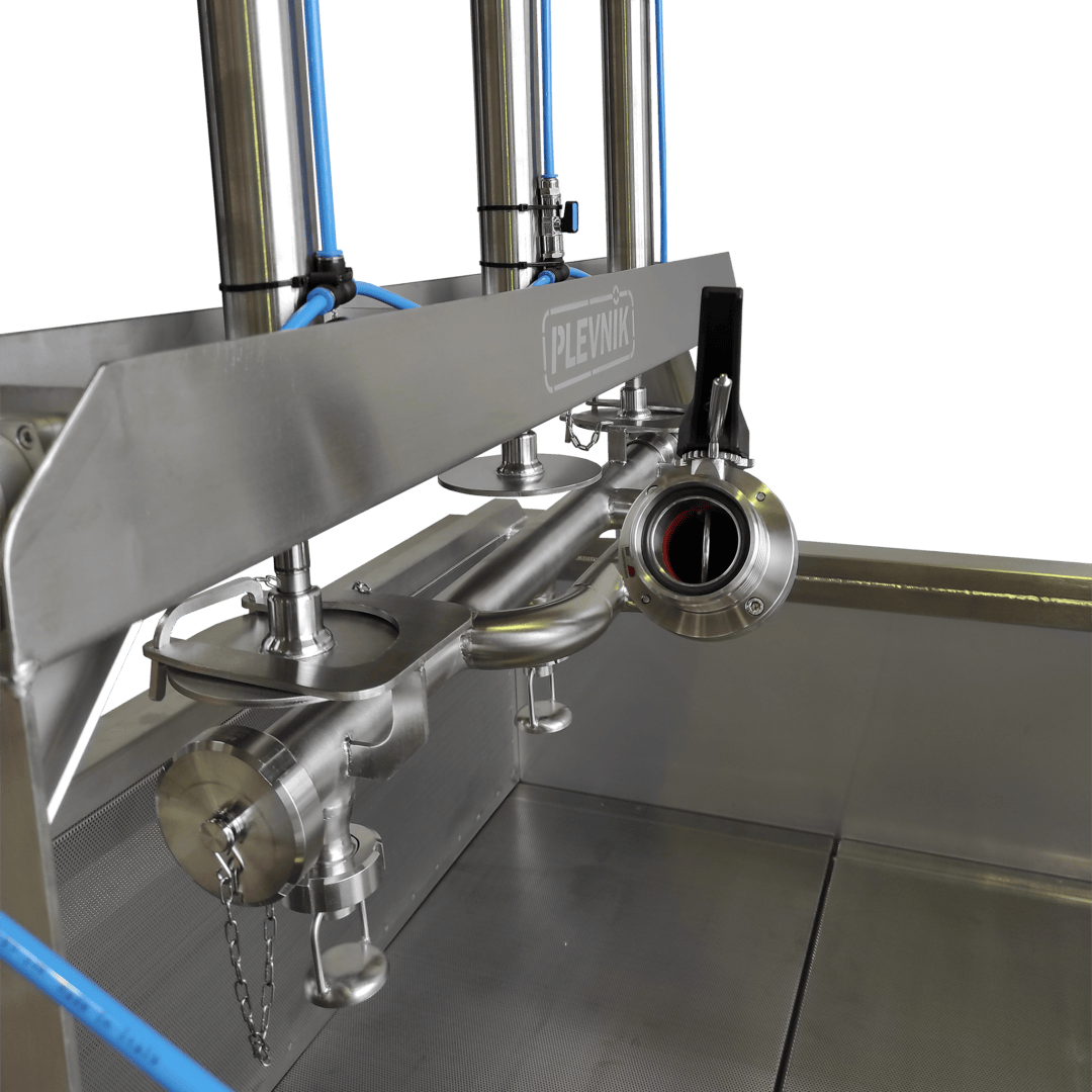 Nahaufnahme einer Industriemaschine aus rostfreiem Stahl mit Rohren, Ventilen und blauen Schläuchen, beschriftet mit "Plevnik", vor einem schlichten, hellen Hintergrund.